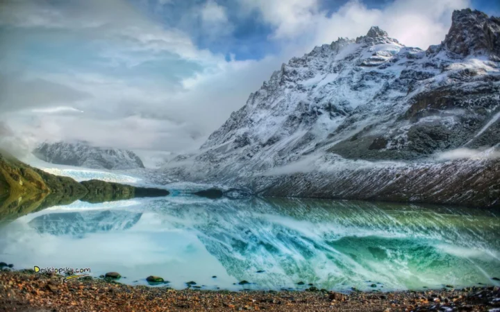 雪覆山峰环绕着宁静的湖泊，湖面倒映出冰川与山体的壮丽景色。