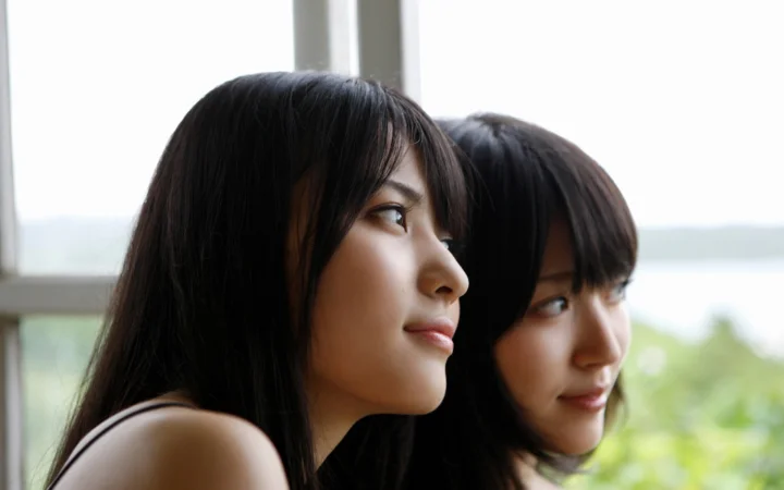 两名女性在窗边并排侧脸望向窗外。