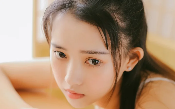 一位深色头发的女性在暖色光线下呈现近距离侧脸肖像。