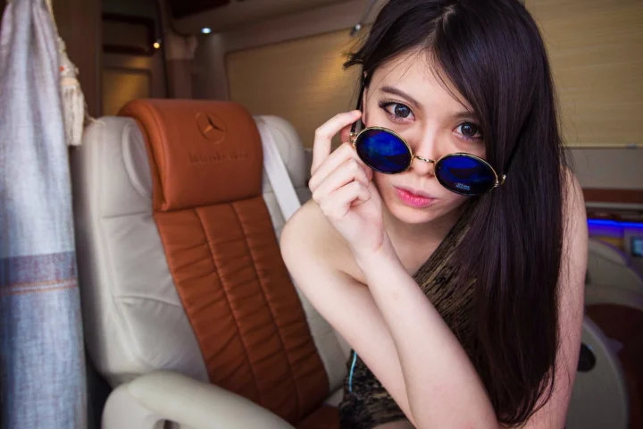 一名长发女性在车内佩戴蓝色镜片的圆形太阳镜。