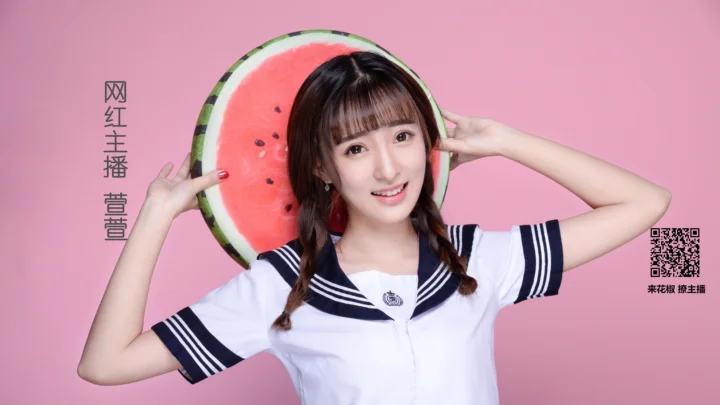 一名女子身穿白色水手风上衣，手托一片西瓜站在粉色背景前。