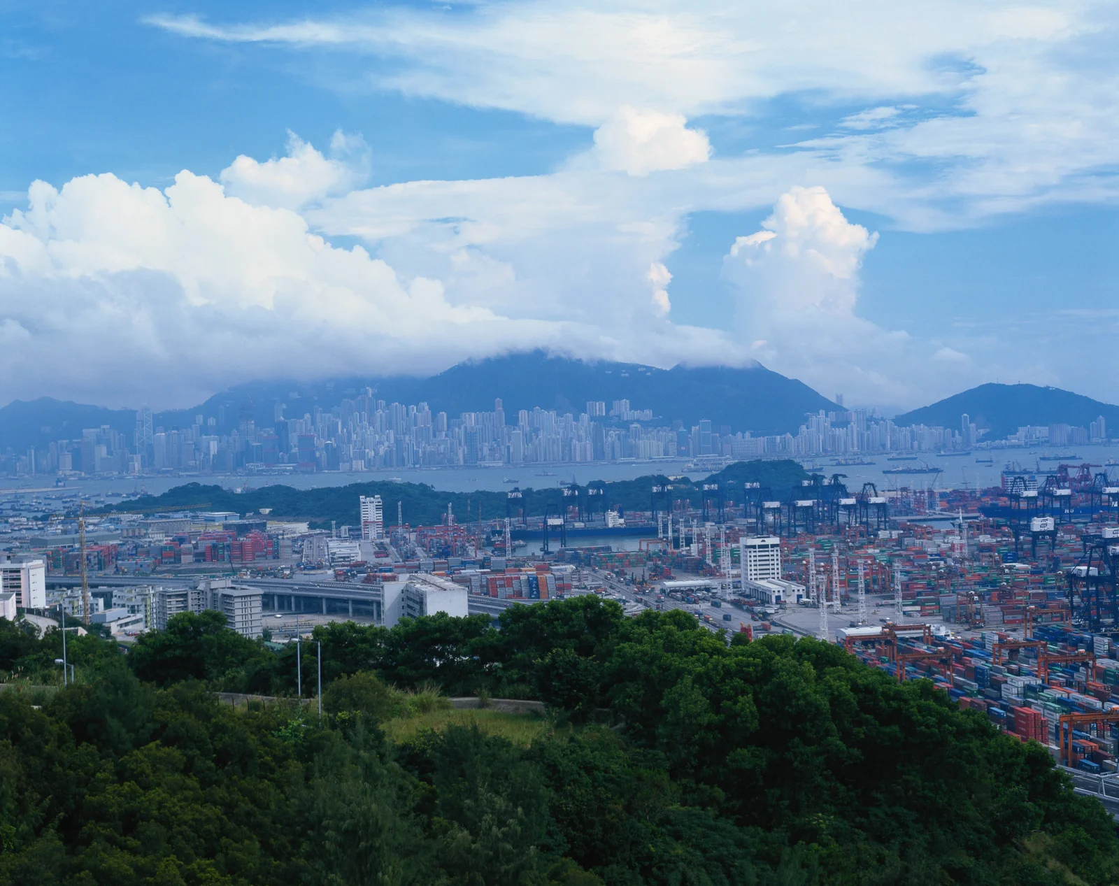 俯瞰繁忙的集装箱港口、城市天际线、远山和云层。