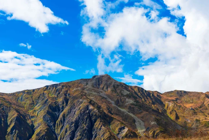 巍峨的山峰延伸在蓝天白云之间。