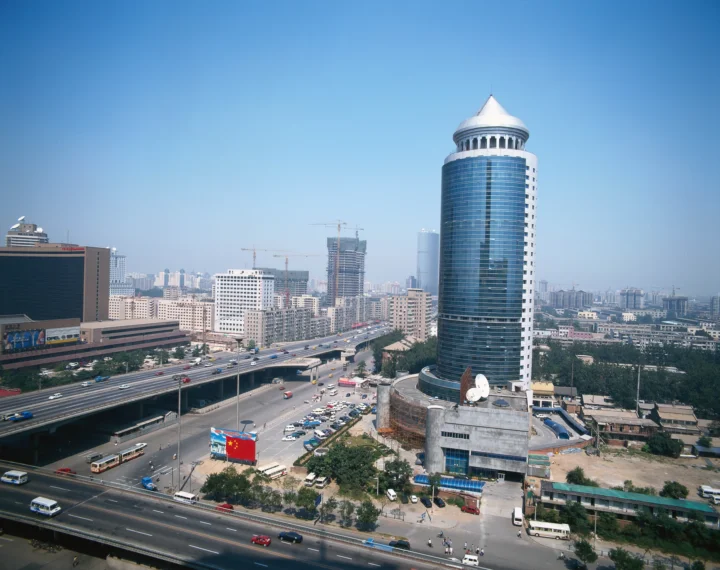 晴朗蓝天下，高架道路、城市建筑群和一座圆顶摩天大楼构成城市景观。