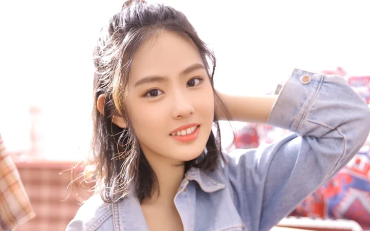 一位成年女性身穿牛仔外套，面向镜头微笑。