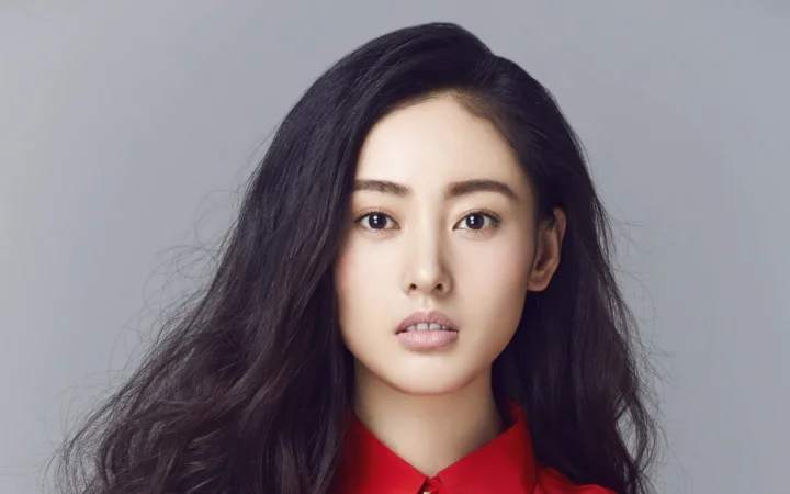 一名成年女性身穿红色衣服，在灰色背景前面对镜头。