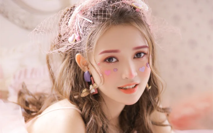 一位戴着精致头纱、脸颊贴有心形装饰的女性在柔和光线下微笑。