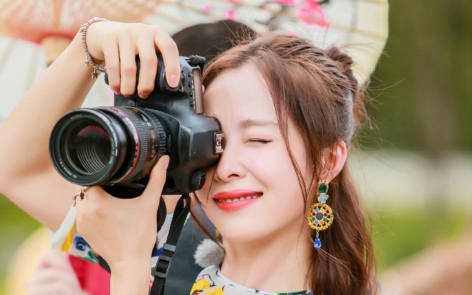 一名女性在户外手持相机拍摄。