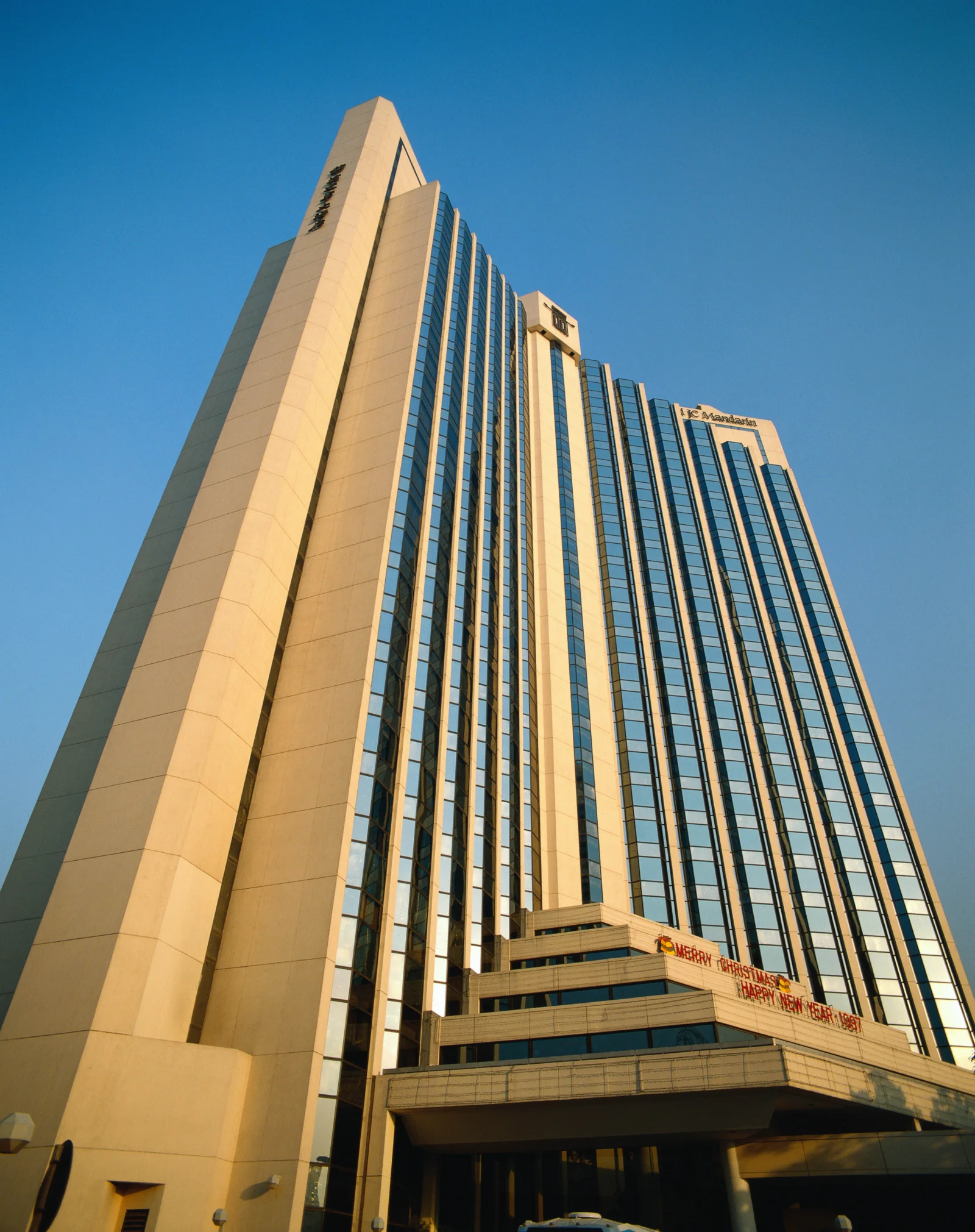 一座现代高层建筑从低角度仰望，矗立在晴朗的蓝天下。