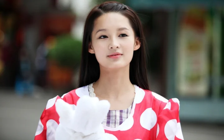 一名成年女性身穿红白波点服装，在虚化背景前面对镜头。