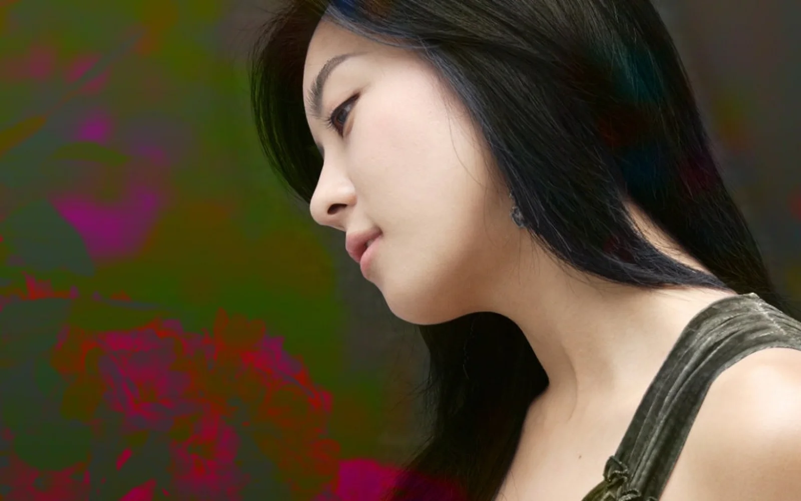 一名黑发女性以侧脸姿态面对左侧，背景为深色虚化色块。