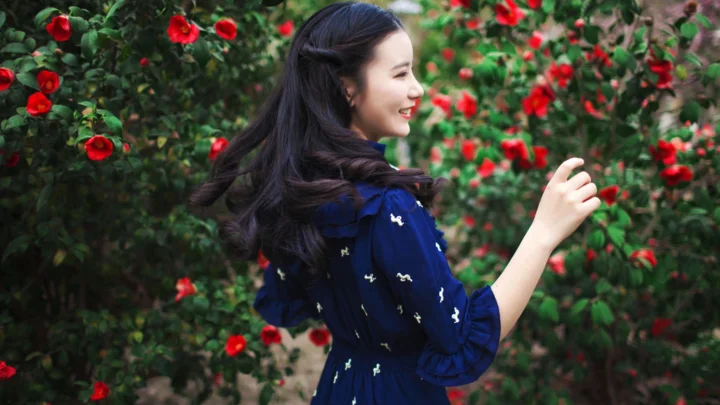 一名女子站在开满红花的花园中。