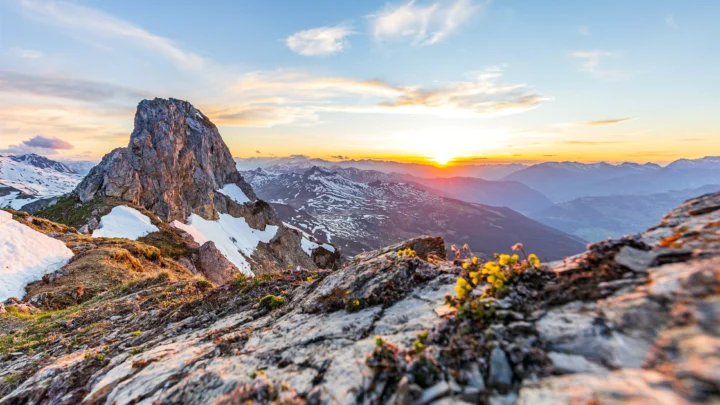 夕阳映照着积雪山峰、岩石山脊和远处的群山。