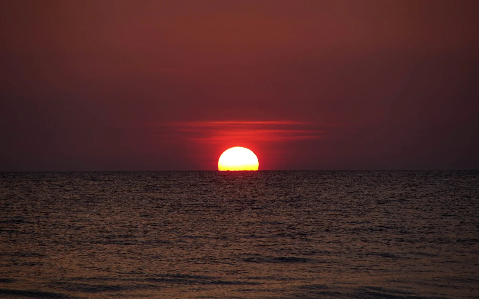 赤い夕日が水平線に沈みかけ、穏やかな海面を照らしている。