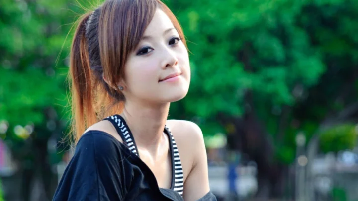 一位成年女性在绿意背景前微笑凝视镜头。