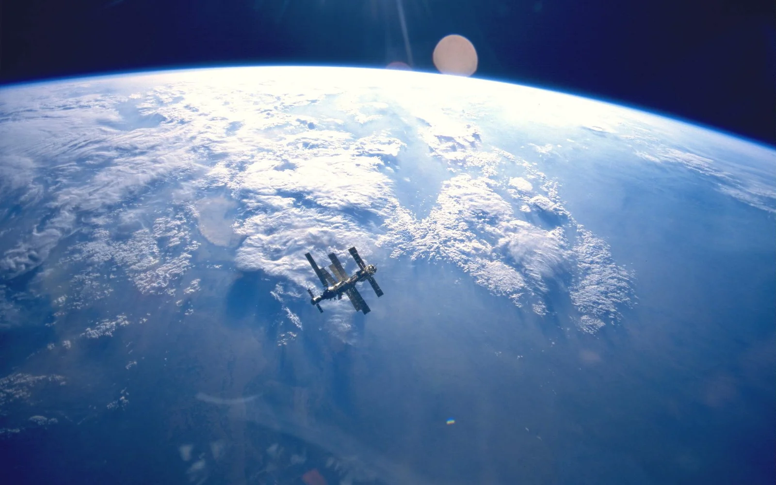 从太空俯瞰地球弧面与云层，一座空间站漂浮在画面中央。