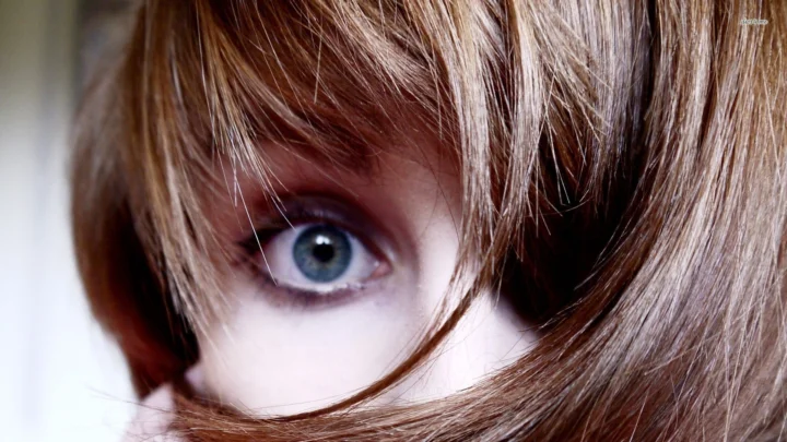画面展示棕色头发与一只蓝色眼睛的近距离特写。