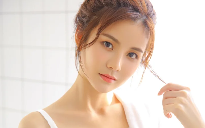 一位成年女性在明亮的窗前轻轻拨弄发丝。