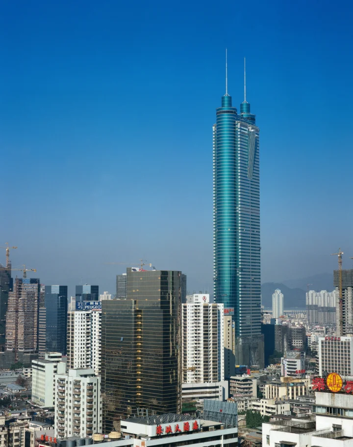 蓝天下，高耸的双塔建筑矗立在密集的城市建筑群中。