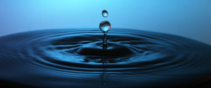 一滴水落在深蓝色水面上，形成层层扩散的涟漪。