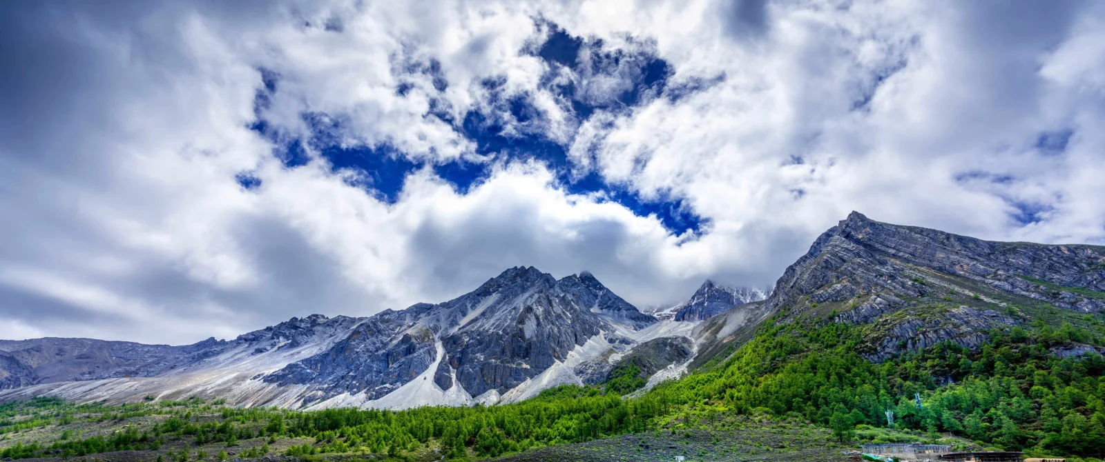 画面展示了群山、森林和厚重云层构成的壮丽自然景观。