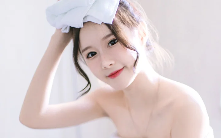 画面中是一位佩戴白色蝴蝶结、面向镜头微笑的女性近距离肖像。