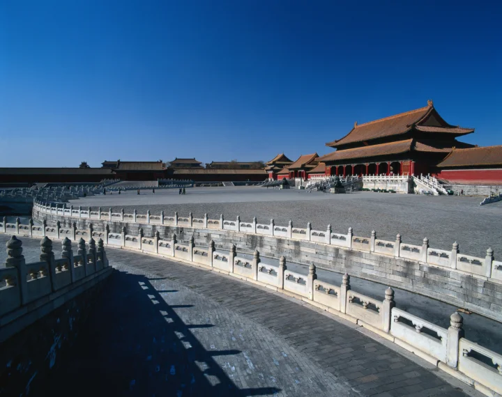 蓝天下的传统宫殿建筑与宽阔石砌庭院。