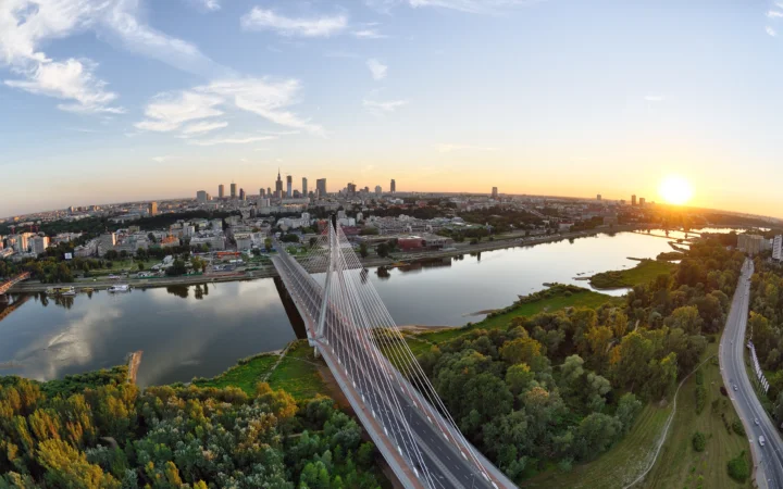 航拍视角展现夕阳下的城市天际线、河流与横跨水面的斜拉桥。