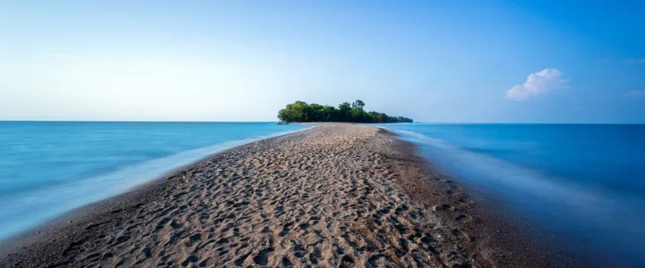 砂州が穏やかな青い海に囲まれた小さな島へと伸びています。