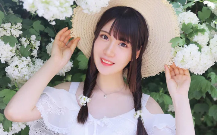 一位戴着草帽、扎着双辫的女性站在白色花朵之间。