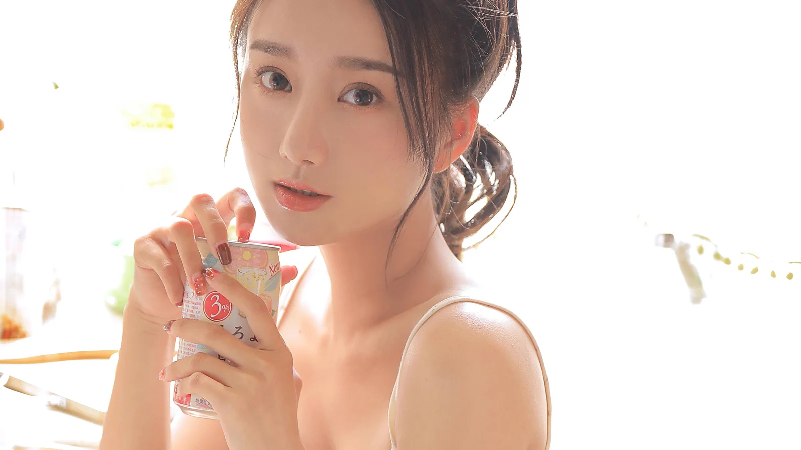 一名女子手持小型饮品容器，在明亮背景前进行近距离肖像拍摄。