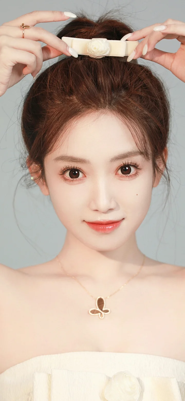 연한 회색 배경 앞에서 흰색 헤어밴드를 착용한 성인 여성이 카메라를 바라보고 있습니다.