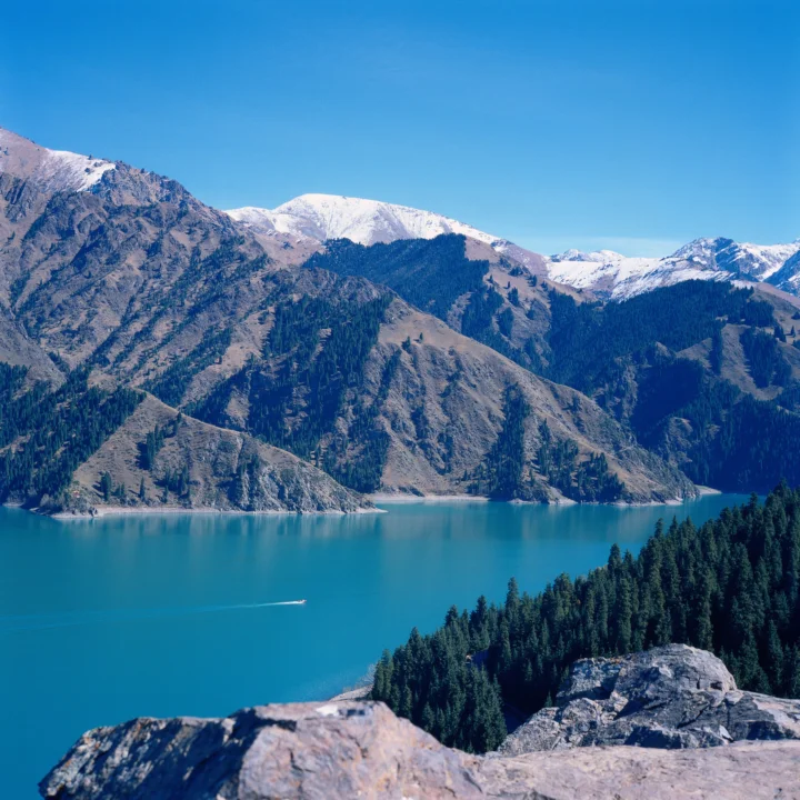 蓝天下的雪山、森林与碧蓝湖泊组成宁静的自然风景。