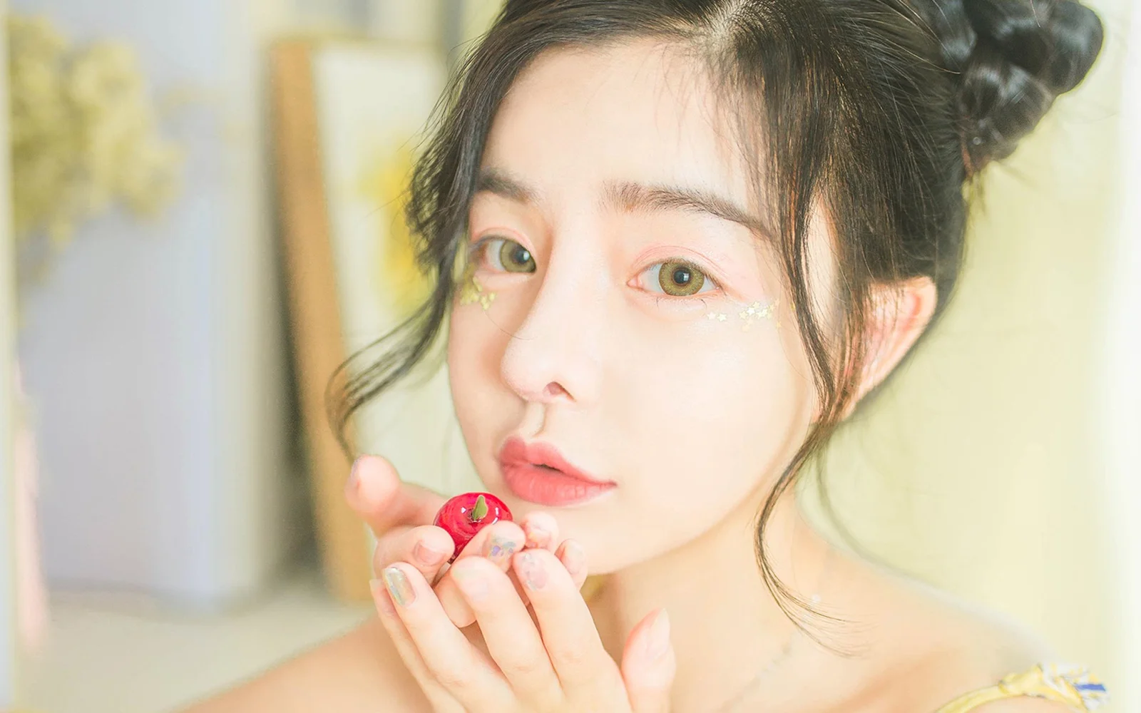 밝고 부드러운 배경 앞에서 빨간 과일을 든 성인 여성이 카메라를 바라보는 클로즈업 인물 사진입니다.
