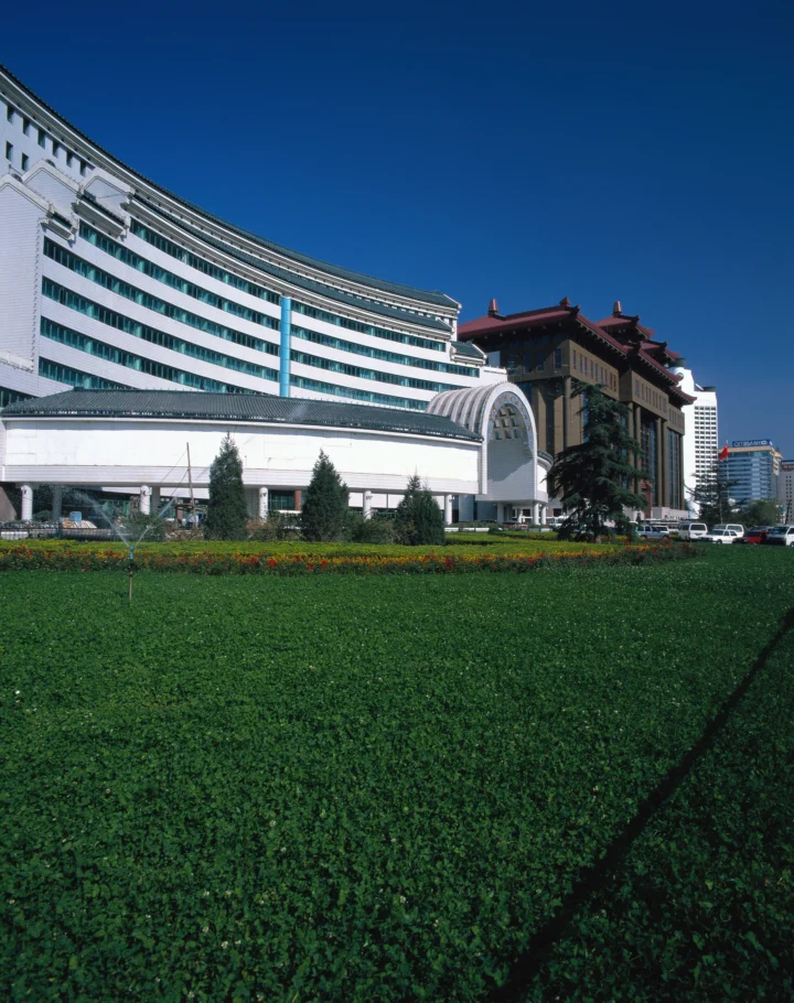 蓝天下的城市建筑坐落在修剪整齐的草坪和花坛后方。