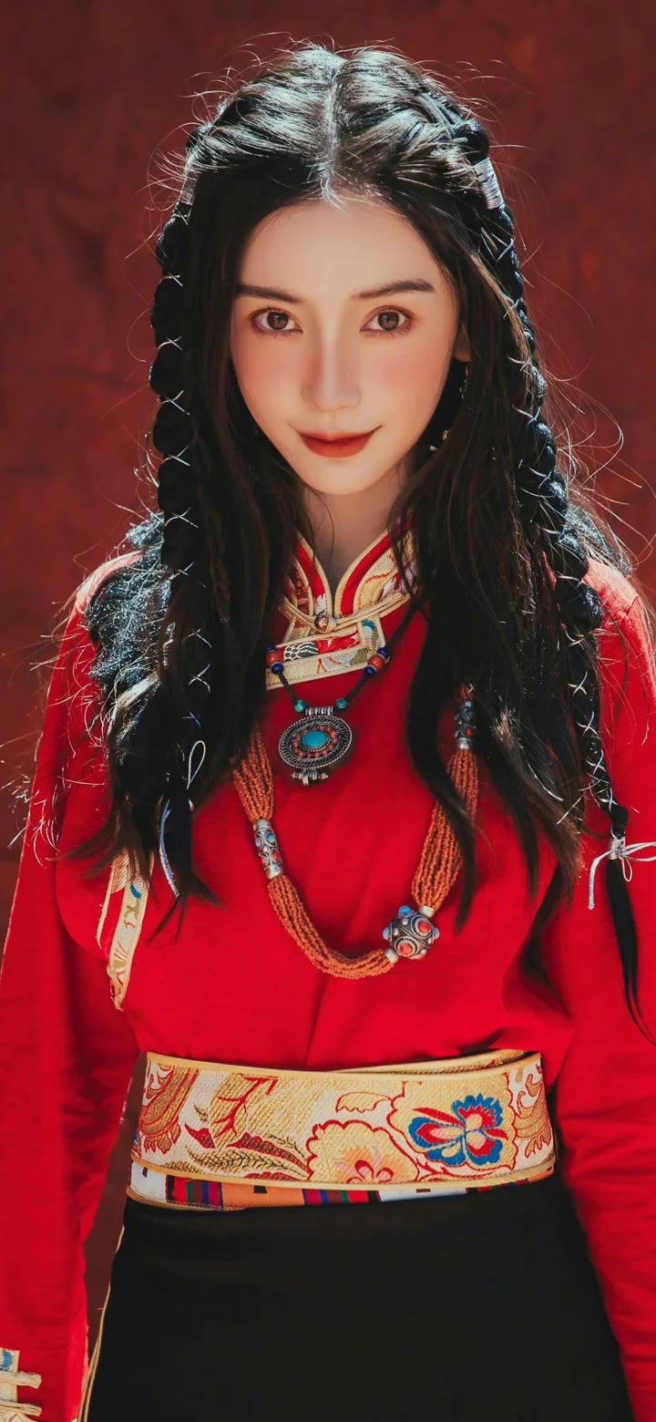 一名长发女子身穿红色传统服饰，站在深红色背景前。