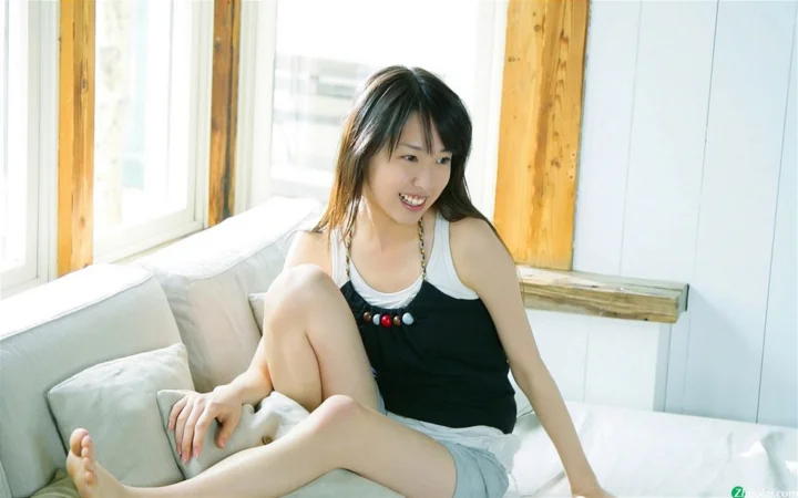 一名女子坐在明亮窗边的沙发上。