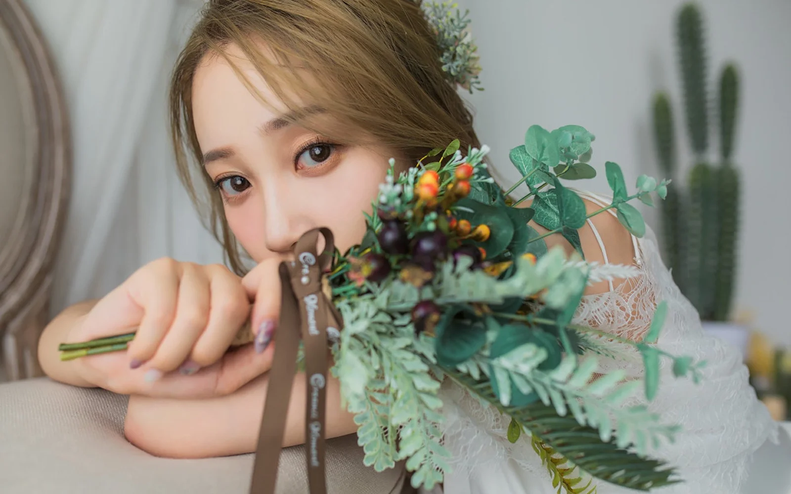 一名成年女性手持花束和剪刀，靠在室内椅背上看向镜头。