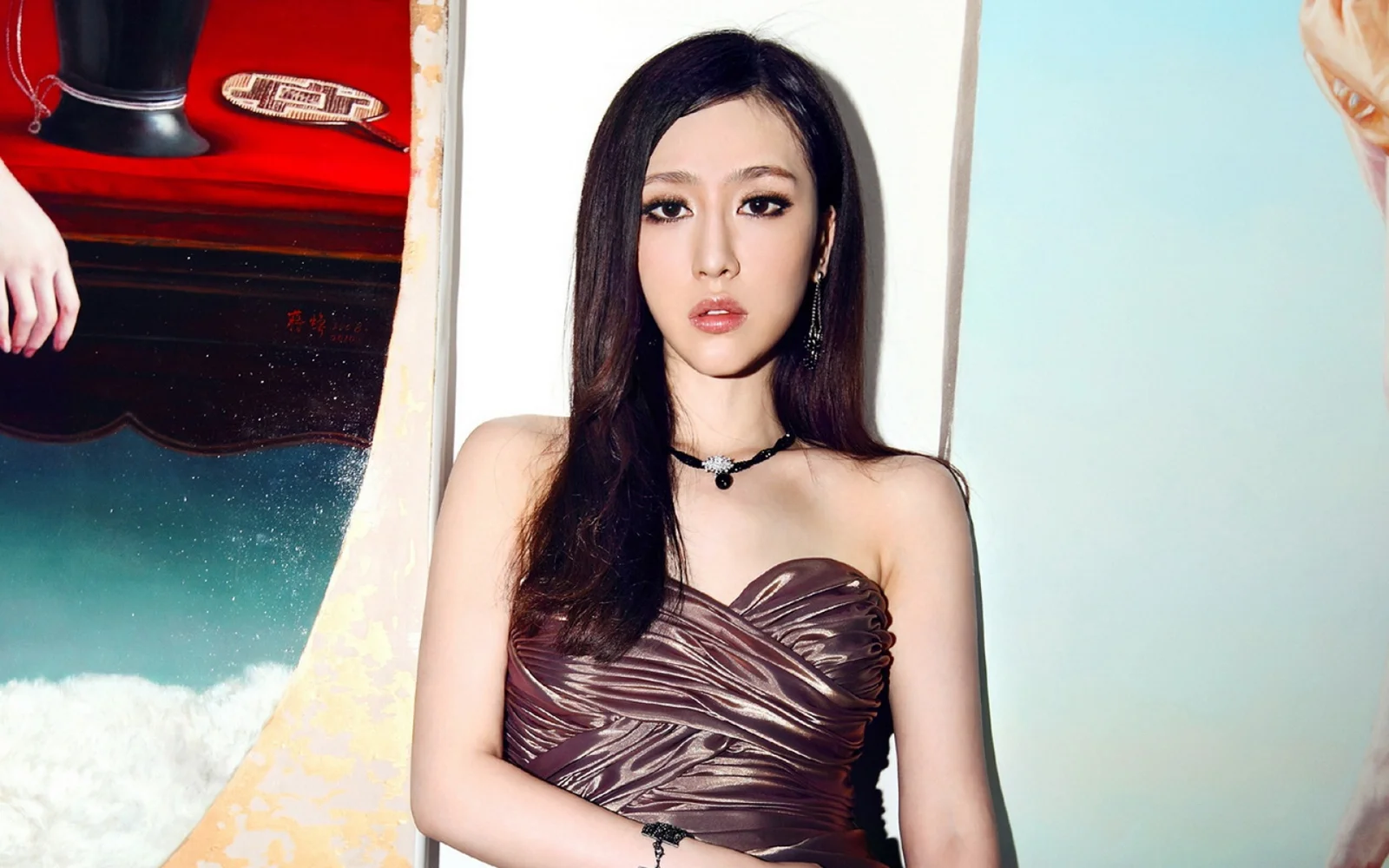 一位長髮女性身穿棕色紋理抹胸禮服，置身於色彩繽紛的背景前。