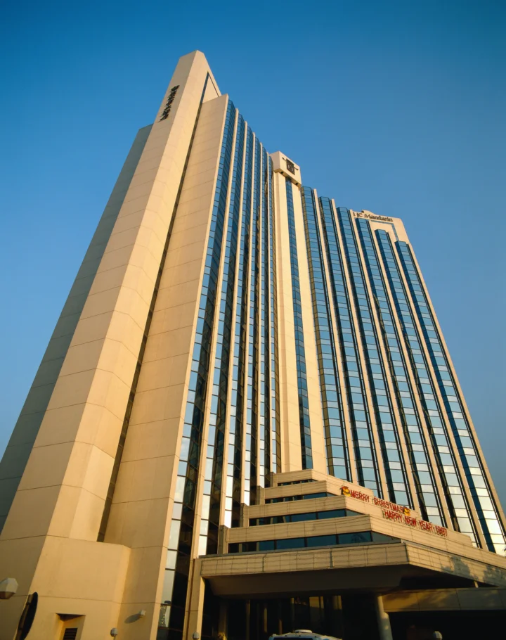一座现代高层建筑从低角度仰望，矗立在晴朗的蓝天下。