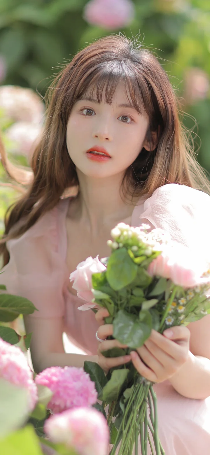 一位长发女子在花朵环绕中手捧一束鲜花。