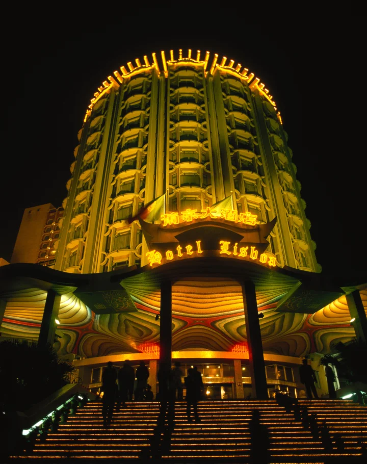夜色中的高层酒店被金色灯光照亮，入口台阶延伸至画面前景。