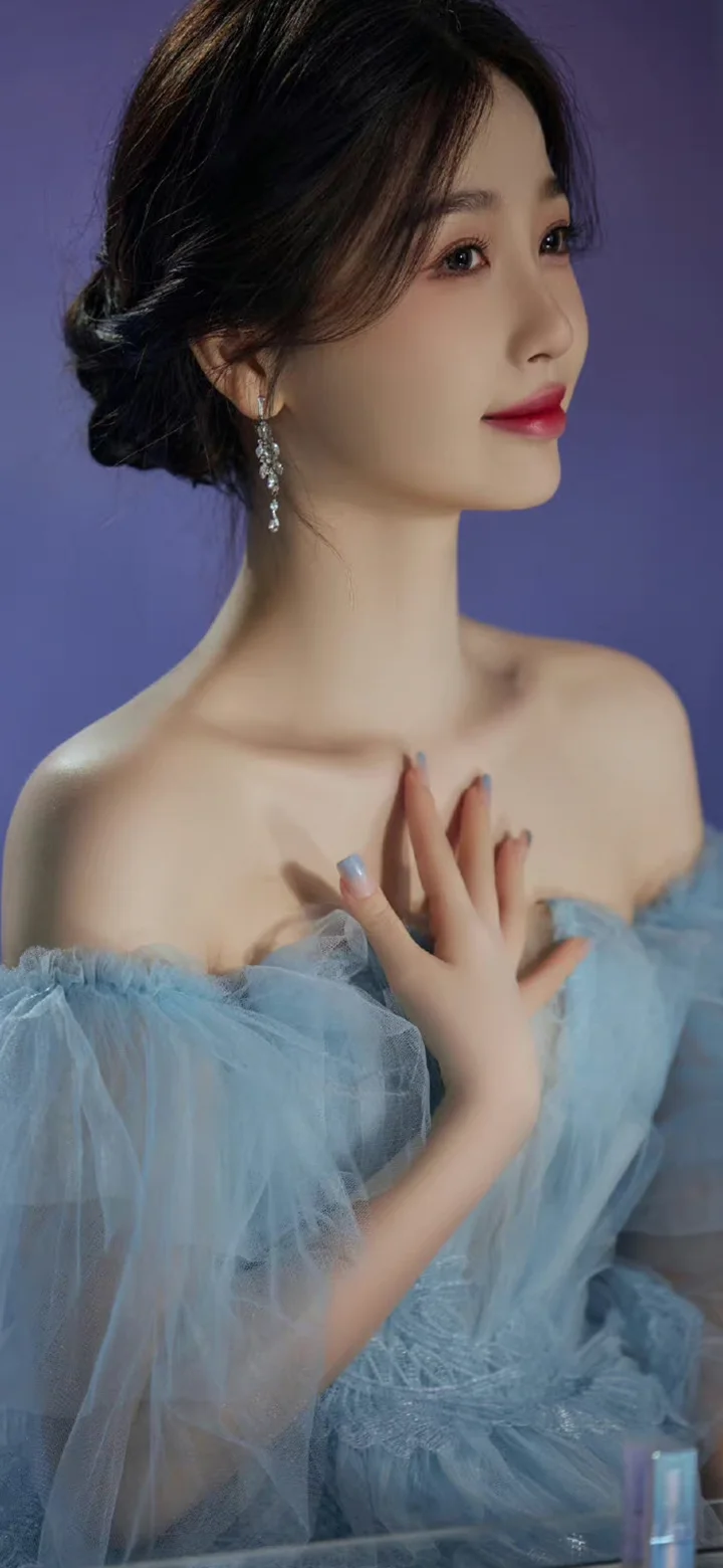 一名成年女性身穿浅蓝色礼服，在紫色背景前侧脸面对镜头。