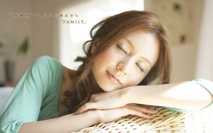 一名成年女性闭眼伏在藤椅上休息。