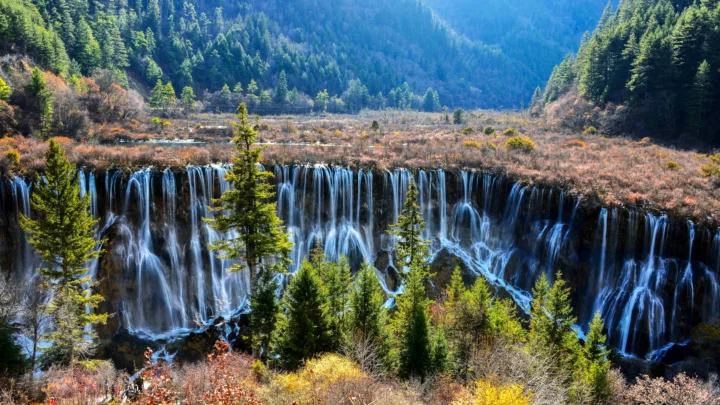 群山森林之间的瀑布从岩壁上倾泻而下。