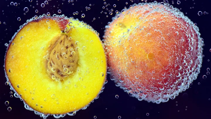 濃密な気泡に覆われた二つの果物が暗い背景に浮かんでいる。