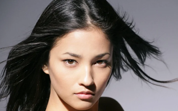 一名黑发成年女性在灰色背景前呈现近距离肖像。