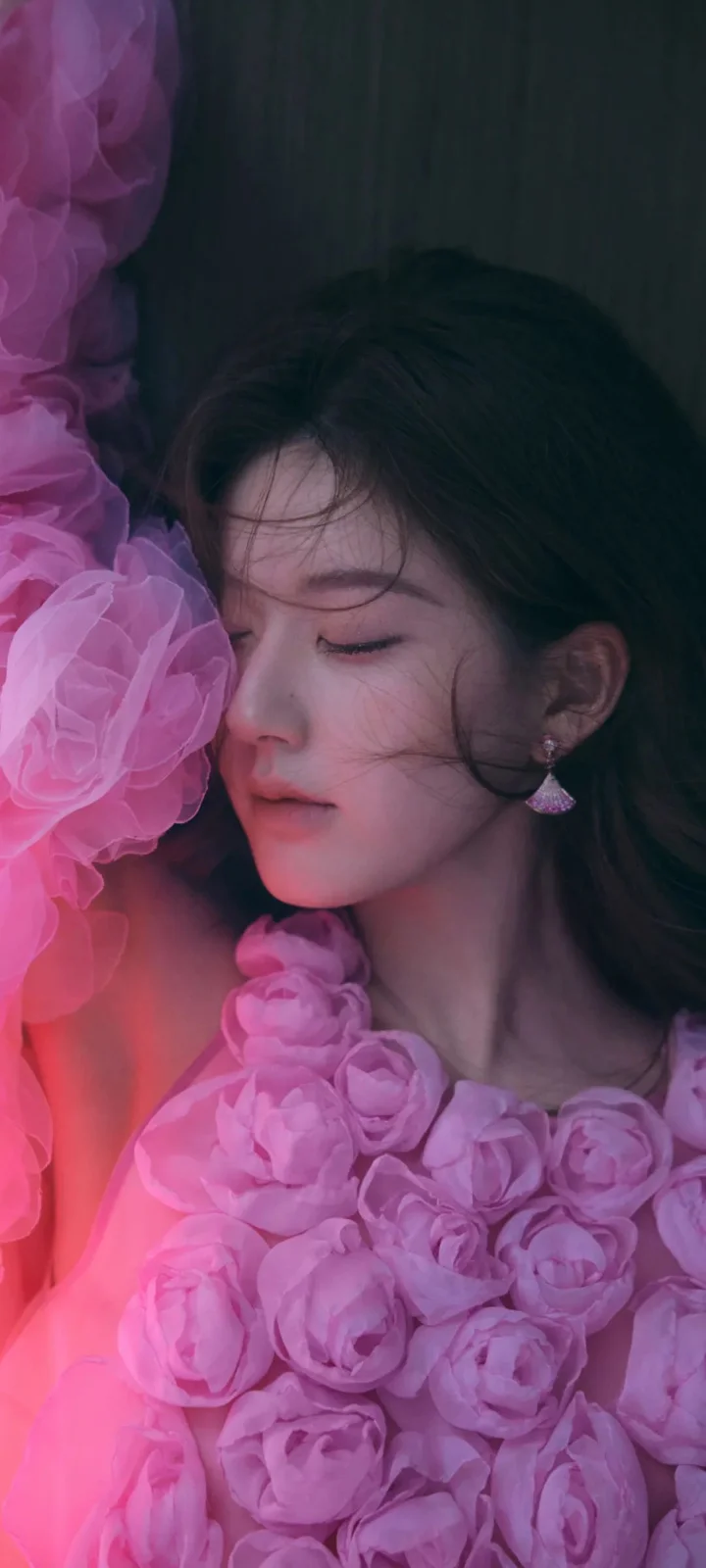 一名女性闭眼靠近粉色花朵，画面以柔和的粉紫色调为主。