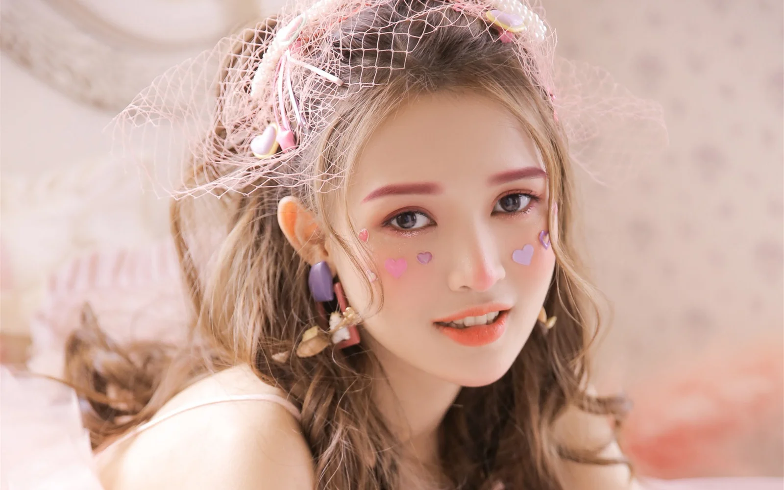 一位戴着精致头纱、脸颊贴有心形装饰的女性在柔和光线下微笑。
