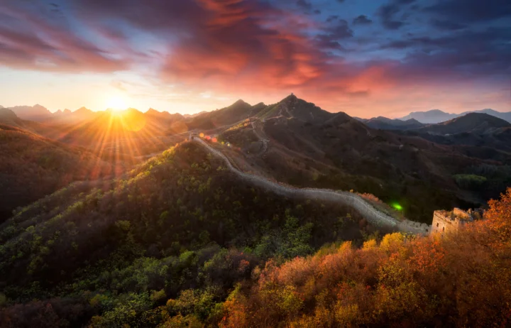 夕阳照耀群山与森林，蜿蜒的长城延伸在山脊之间。